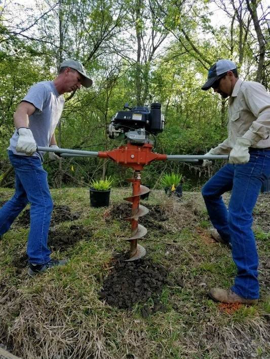 Lucas Gregory, Ph.D., TWRI senior research scientist, and Ward Ling, formerly the Geronimo and Alligator Creeks watershed coordinator, use an auger to dig large holes in a more efficient manner to plant numerous large pots of native Indian sea oats.